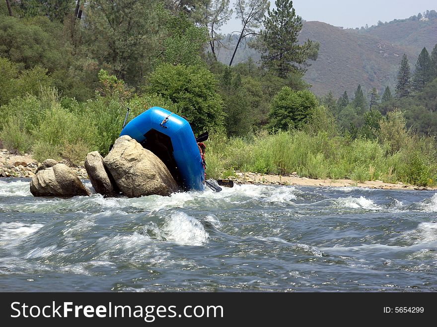 River rafters miss the channel and get hung up on boulders rafting down the American river. River rafters miss the channel and get hung up on boulders rafting down the American river