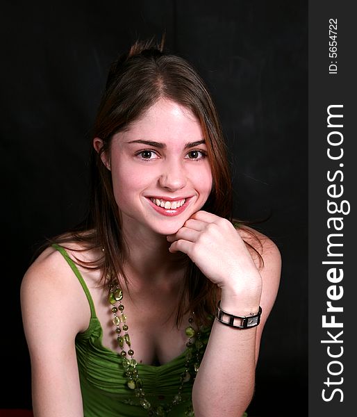 Portrait of a smiling beautiful teenage girl with green beads on her neck against black back-ground. Portrait of a smiling beautiful teenage girl with green beads on her neck against black back-ground.