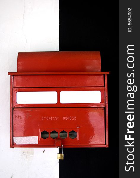 A letter box in front of a black and white wall