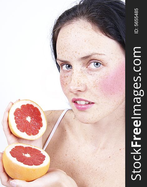 Portrait of a beautiful brunette woman with light grey eyes and freckles on her skin holding a grapefruit. Portrait of a beautiful brunette woman with light grey eyes and freckles on her skin holding a grapefruit