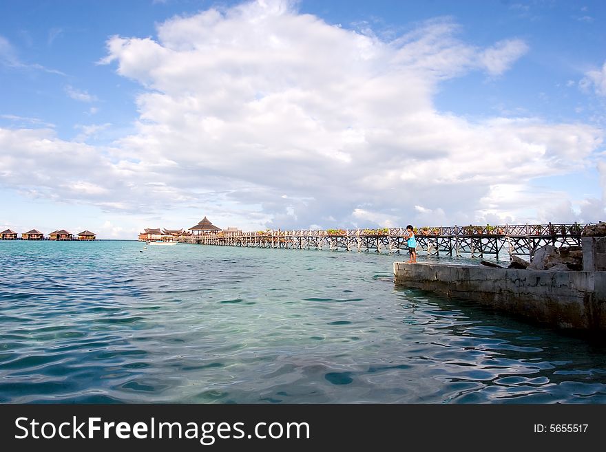 Tropical seascape with a boy and a bridge to water bungalows  an indonesian island.