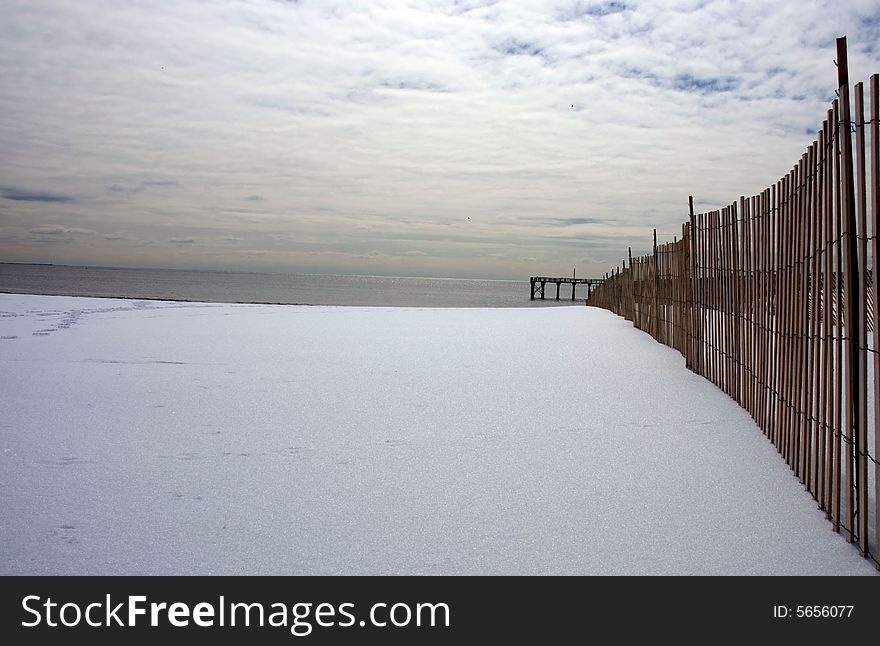 Pier At Shore In Winter With Gloomy Sky