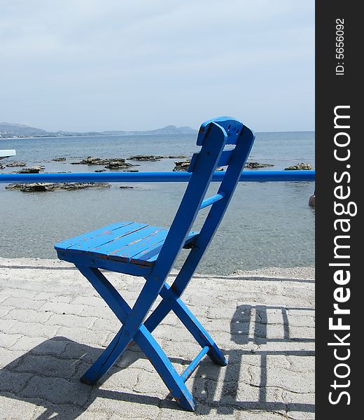 Blue wooden chair in front of a sea