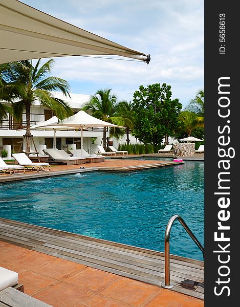 White trestle-beds and umbrellas near the resort's pool. White trestle-beds and umbrellas near the resort's pool