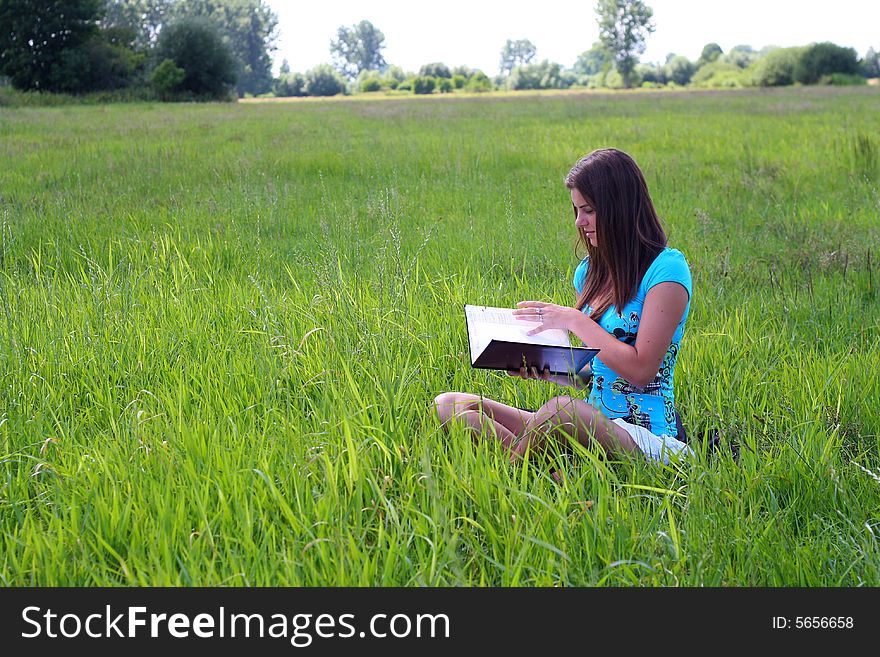 Young woman on the meadow in the summer reading a book. Young woman on the meadow in the summer reading a book.
