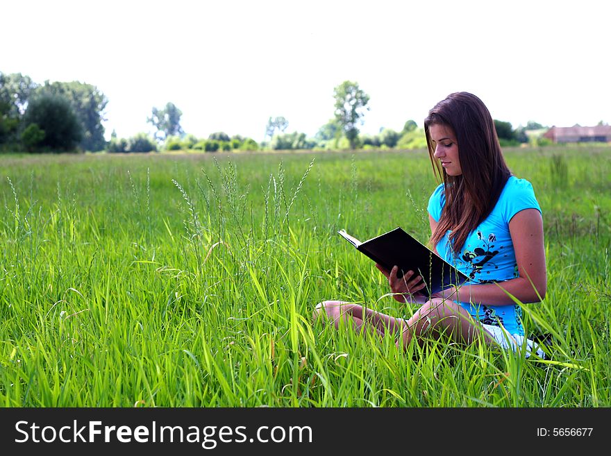 Young woman on the meadow in the summer reading a book. Young woman on the meadow in the summer reading a book.