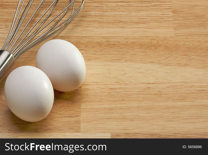 Whisk and Eggs on a wooden background. Room for your own text.