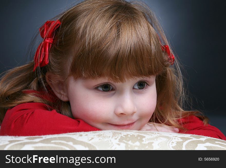 Pretty little girl in red peeking over the arm of a white couch. Pretty little girl in red peeking over the arm of a white couch