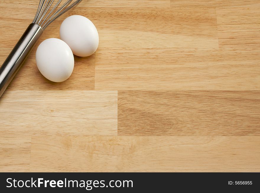 Whisk and Eggs on a wooden background. Room for your own text.