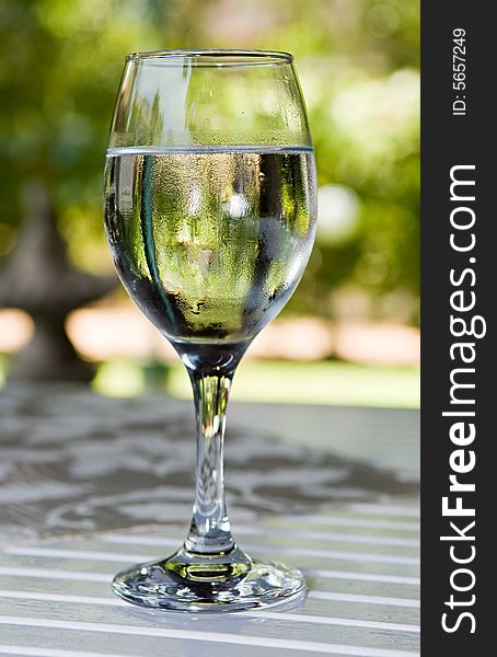 Glass of cold water on garden table in hot summer