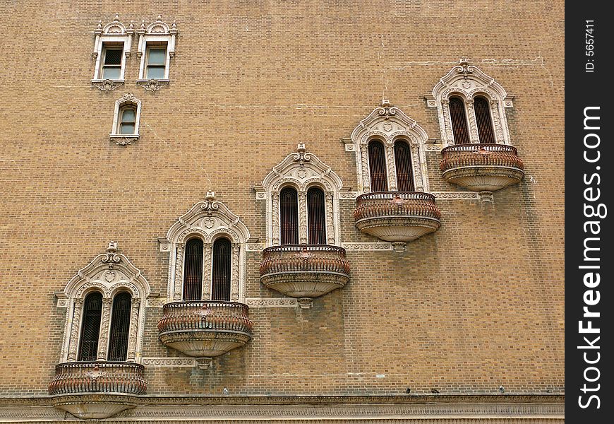 Strangely decorated windows forming a diagonal pattern on a large empty brick wall. Strangely decorated windows forming a diagonal pattern on a large empty brick wall