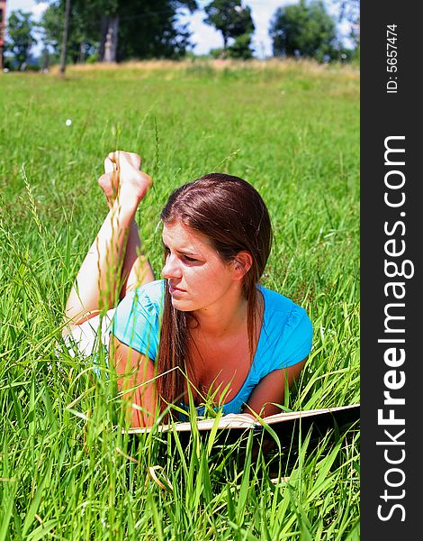 Young woman on the meadow in the summer reading a book. Young woman on the meadow in the summer reading a book.