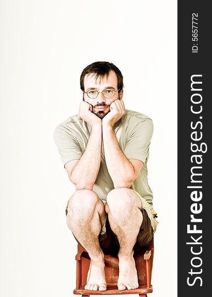 A man in his mid thirties, sitting on a feeding chair.