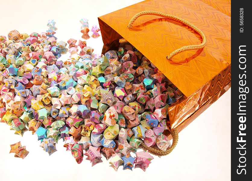 Assorted colored paper stars spill from shiny patterned orange box. Assorted colored paper stars spill from shiny patterned orange box