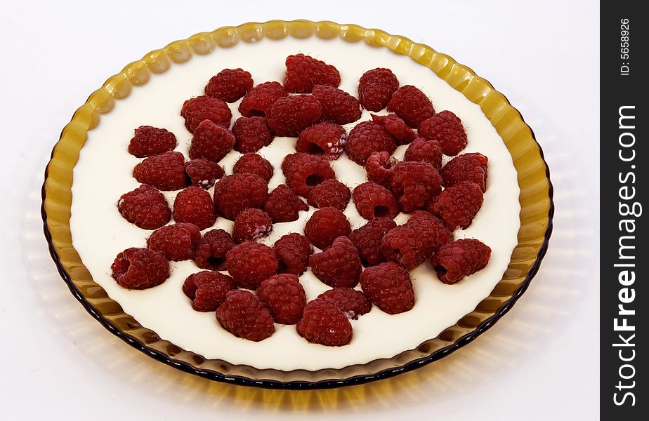 Much ripe red raspberry in a dish with sour cream