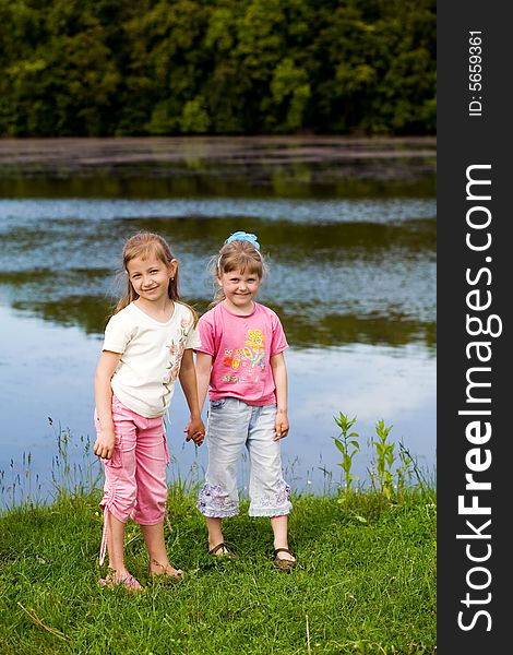 Two little girls on a bank of a river