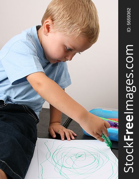 Toddler drawing on a white sheet with a green pen