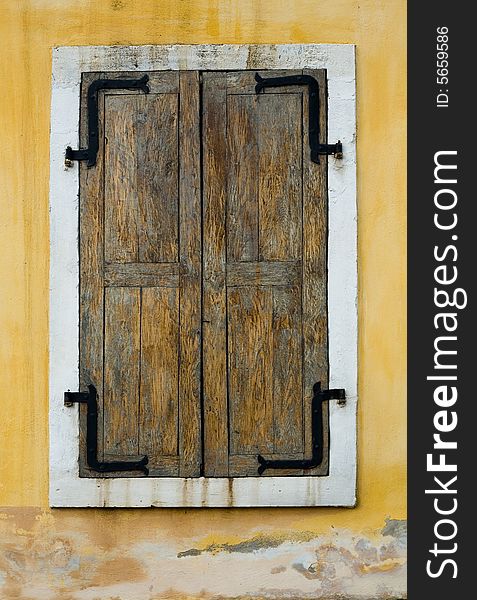 An image of wooden window closed on yellow wall