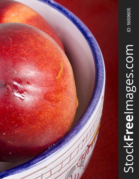 Fresh peaches in bowl on red background