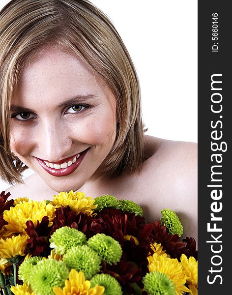 Beautiful blonde woman with bright makeup smiling from behind a bunch of colorful flowers