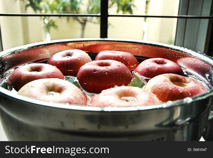 Fresh red apples floating on water beside kitchen window