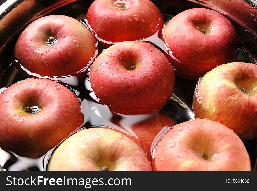 Fresh red apples floating on water in container