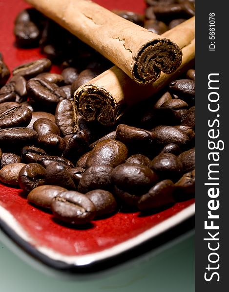 Coffee beans and cinnamon sticks on red plate. Coffee beans and cinnamon sticks on red plate