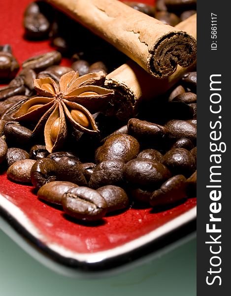 Coffee beans and cinnamon sticks on red plate with anice. Coffee beans and cinnamon sticks on red plate with anice