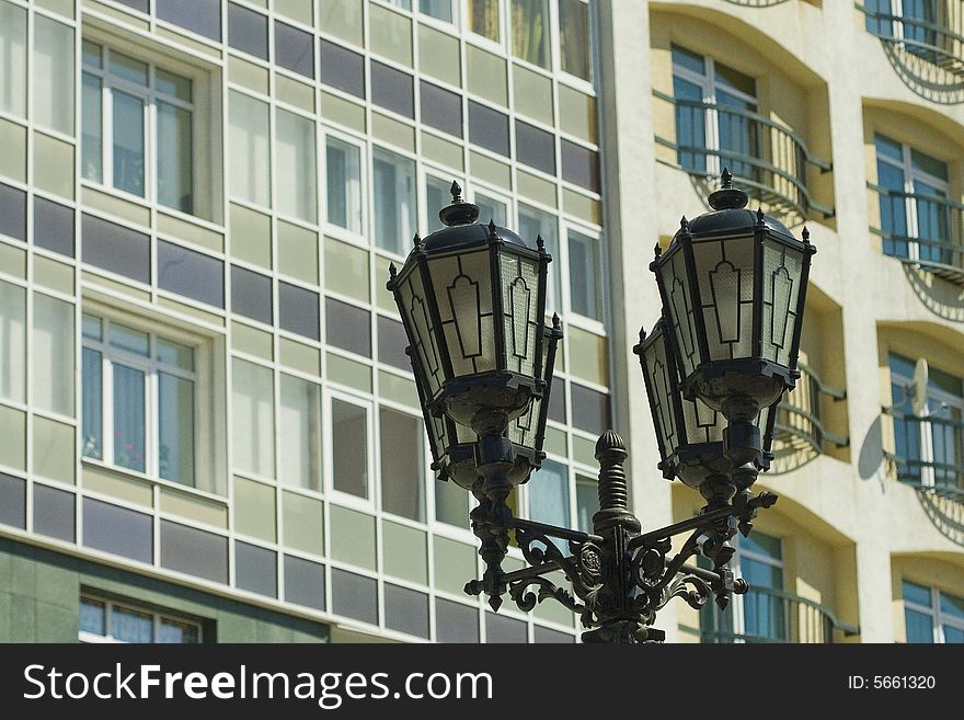 Old street lamp stands beside a new modern building