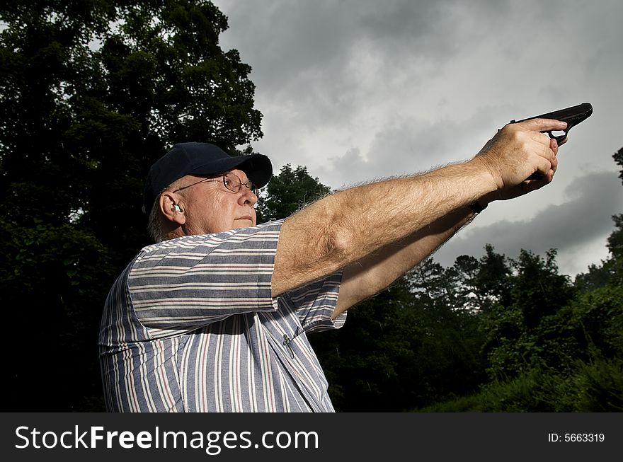 An older man practising his pistol marksmanship.