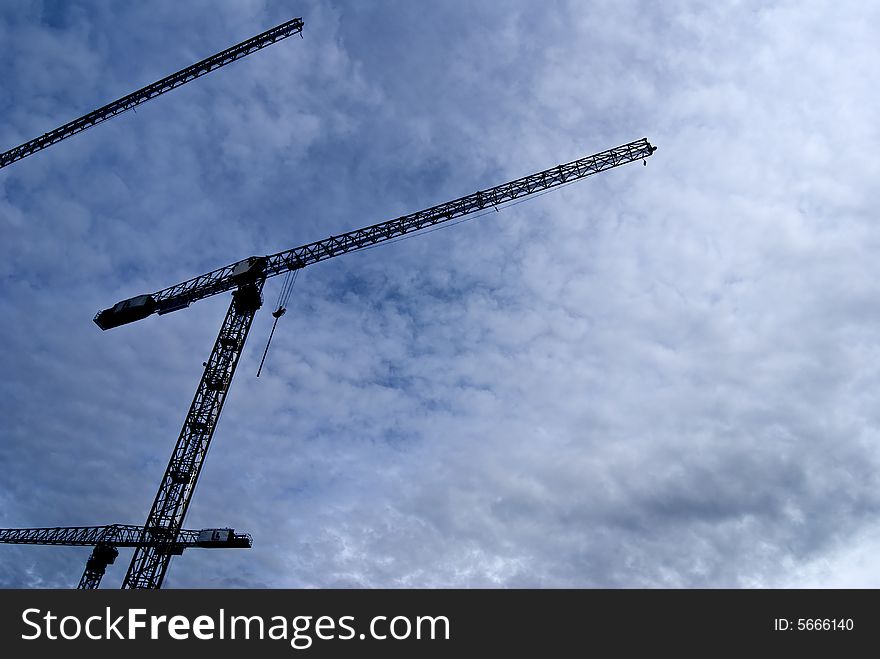 Big construction cranes silhouette midday