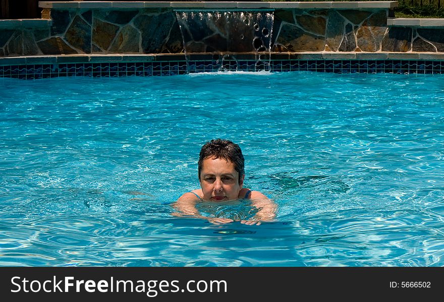 Middle aged woman swimming towards the camera in pool. Middle aged woman swimming towards the camera in pool