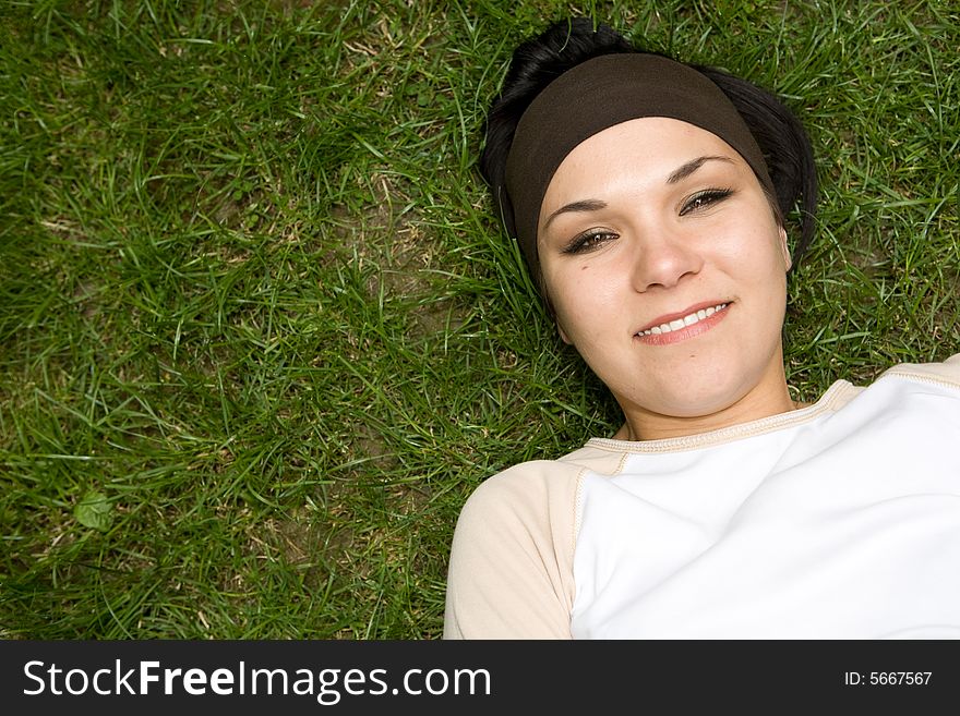 Attractive brunette woman lying on grass. Attractive brunette woman lying on grass