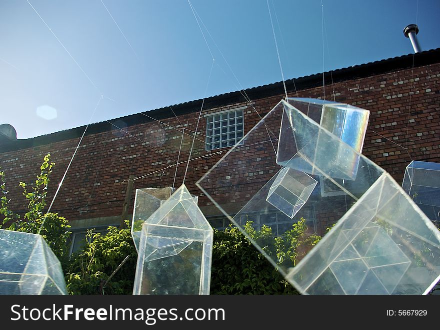 Installation art piece with floating perspex houses suspended on wire to look like polygonal soap bubbles, nine against brick and sky background. Installation art piece with floating perspex houses suspended on wire to look like polygonal soap bubbles, nine against brick and sky background
