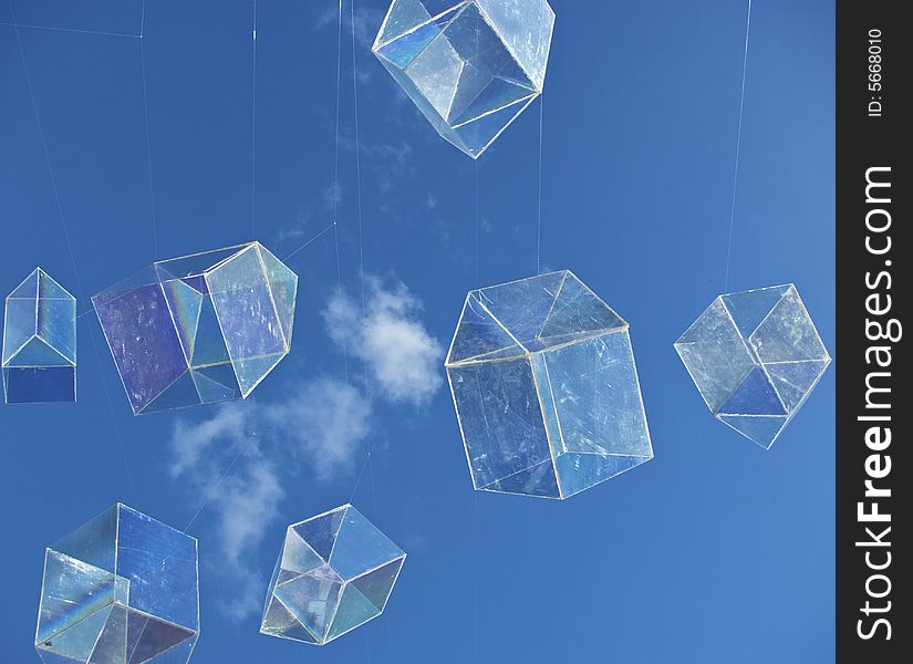 Installation art piece with floating perspex houses suspended on wire to look like polygonal soap bubbles, against blue sky with fluffy cloud. Installation art piece with floating perspex houses suspended on wire to look like polygonal soap bubbles, against blue sky with fluffy cloud