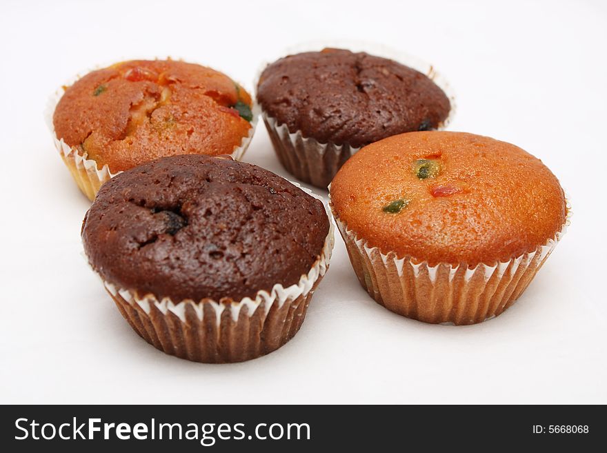 Four different flavor muffins put together on white background.