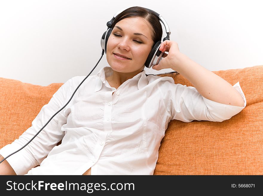 Attractive brunette woman with headphones on sofa. Attractive brunette woman with headphones on sofa