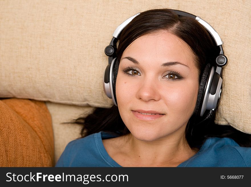 Attractive brunette woman with headphones on sofa. Attractive brunette woman with headphones on sofa