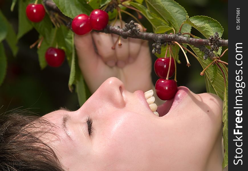 Beautiful young lady eats red cherry just from tree. Beautiful young lady eats red cherry just from tree