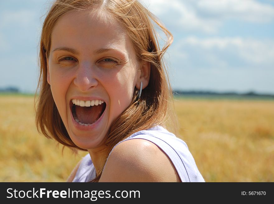 Beautiful young woman laughing on the field background. Beautiful young woman laughing on the field background