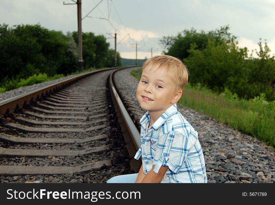 The boy sits on the railway. The boy sits on the railway