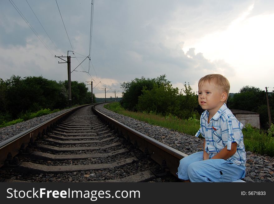 The boy sits on the railway. The boy sits on the railway