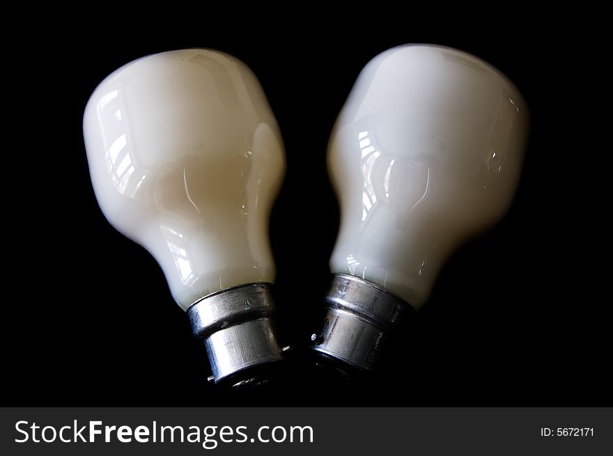 A coupe of saving white electric bulbs isolated in a black background. A coupe of saving white electric bulbs isolated in a black background