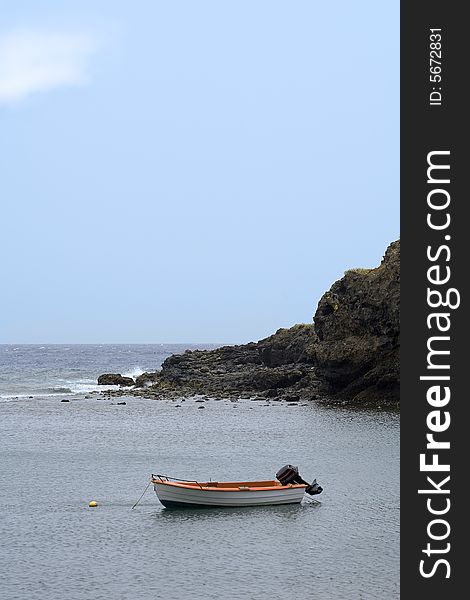 Small boat towed at buoy in rocky bay. Small boat towed at buoy in rocky bay