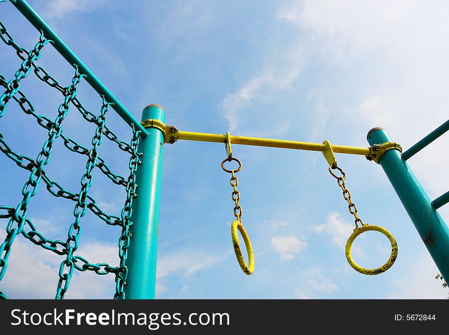 The swinging ring of fitness equipment with a blue sky background in a park .