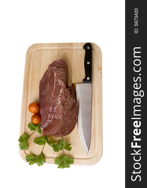 Piece of raw beef with tomatoes and parsley on  wooden board