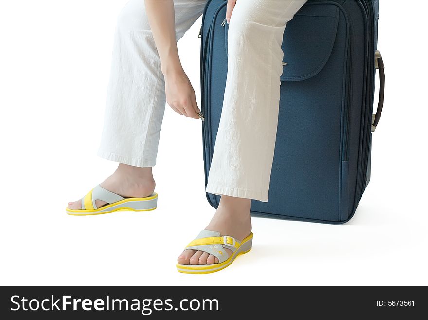 Female sitting on a  suitcase and zipping or unzipping it. Female sitting on a  suitcase and zipping or unzipping it