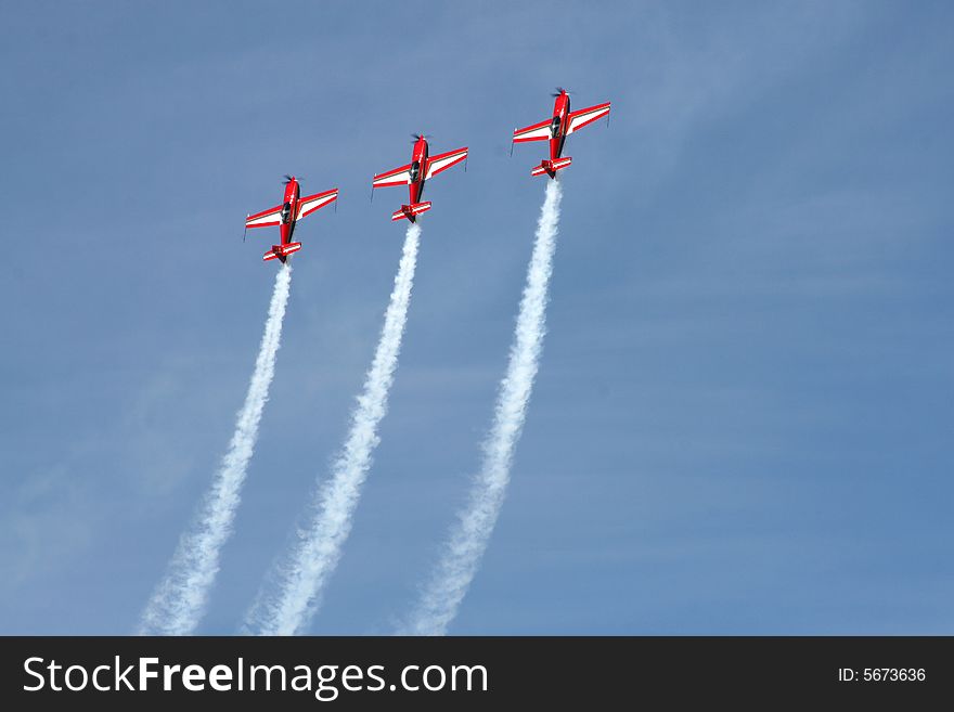 Formation aerobatics aircraft climbing in unison with smoke trails