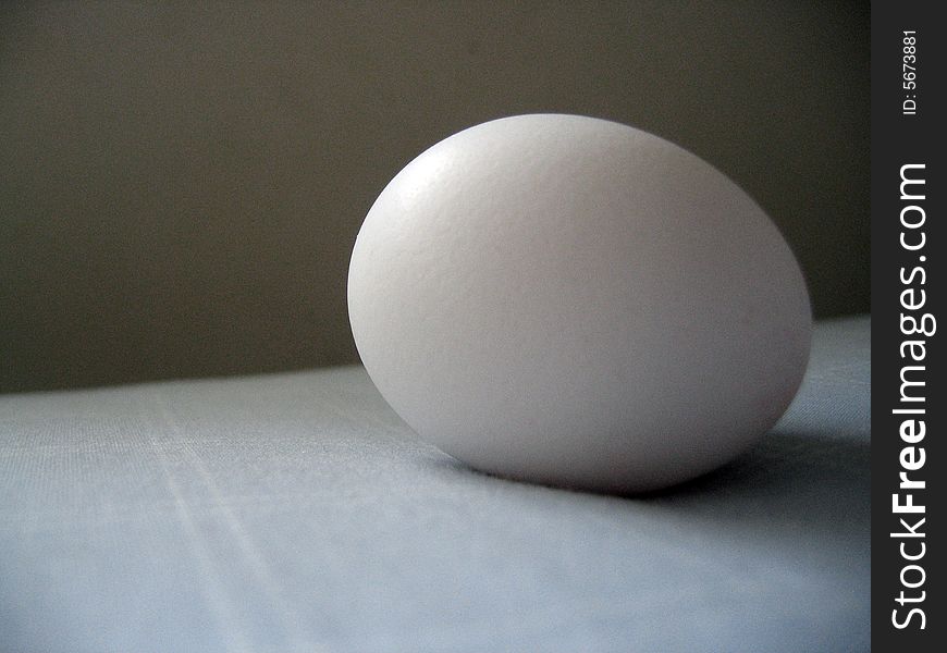 An egg resting on a bed in natural light. An egg resting on a bed in natural light