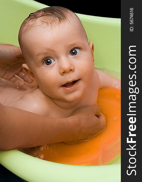 Adorable infant (a boy) lying in green bathtub and rising his head. Adorable infant (a boy) lying in green bathtub and rising his head